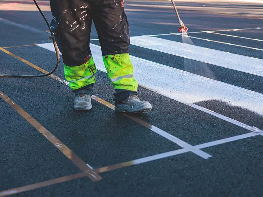 man performing parking lot striping for ada parking lot compliance