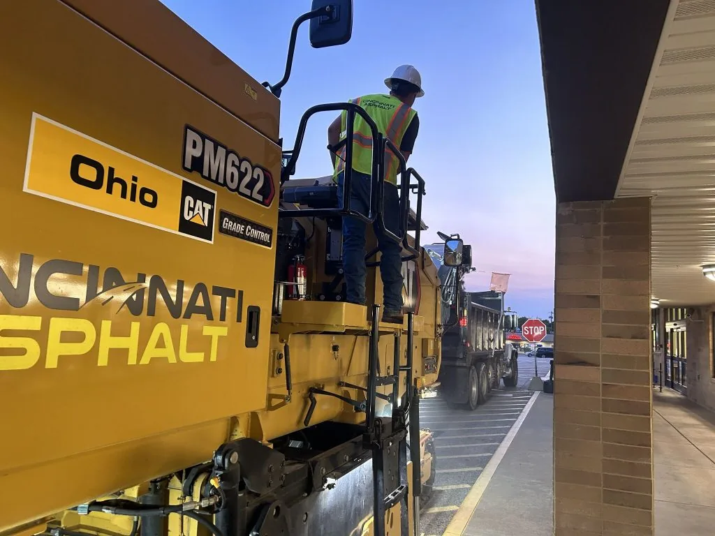 paving contractor employee on a heavy machine that has cincinnati asphalt on the side