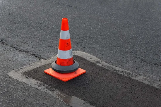 traffic cone on damaged asphalt pavement before pothole repair